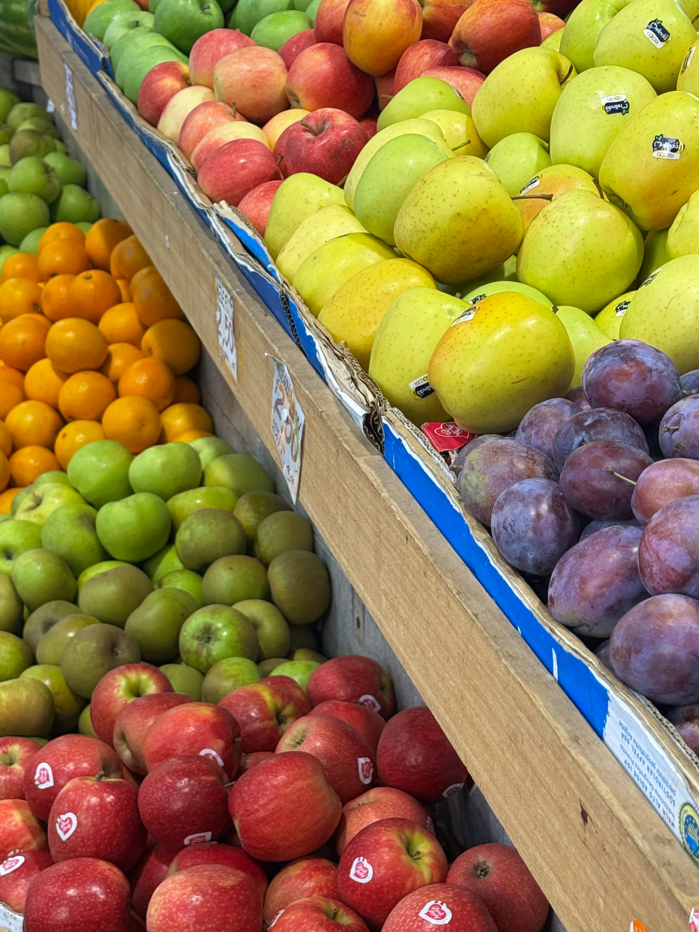 Crates of apples, plums and mandarins at an Italian market, seasonal eating with a Mediterranean nutritionist Gold Coast