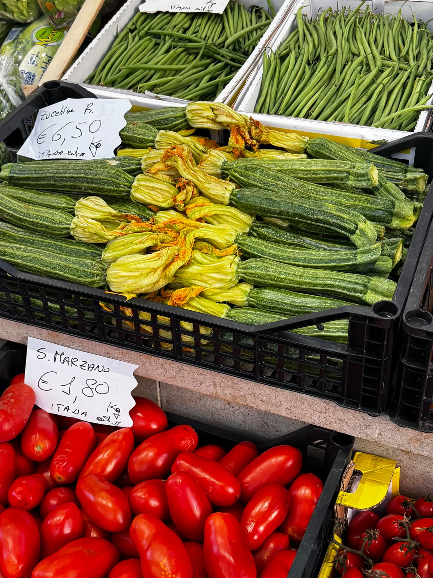 Courgettes with their flowers and San Marzano tomatoes in crates at an Italian market, chosen by a Mediterranean nutritionist Gold Coast